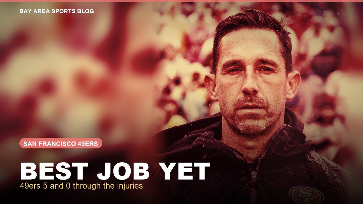 Kyle Shanahan in a rain soaked 49ers jacket behind the words Best Job Yet