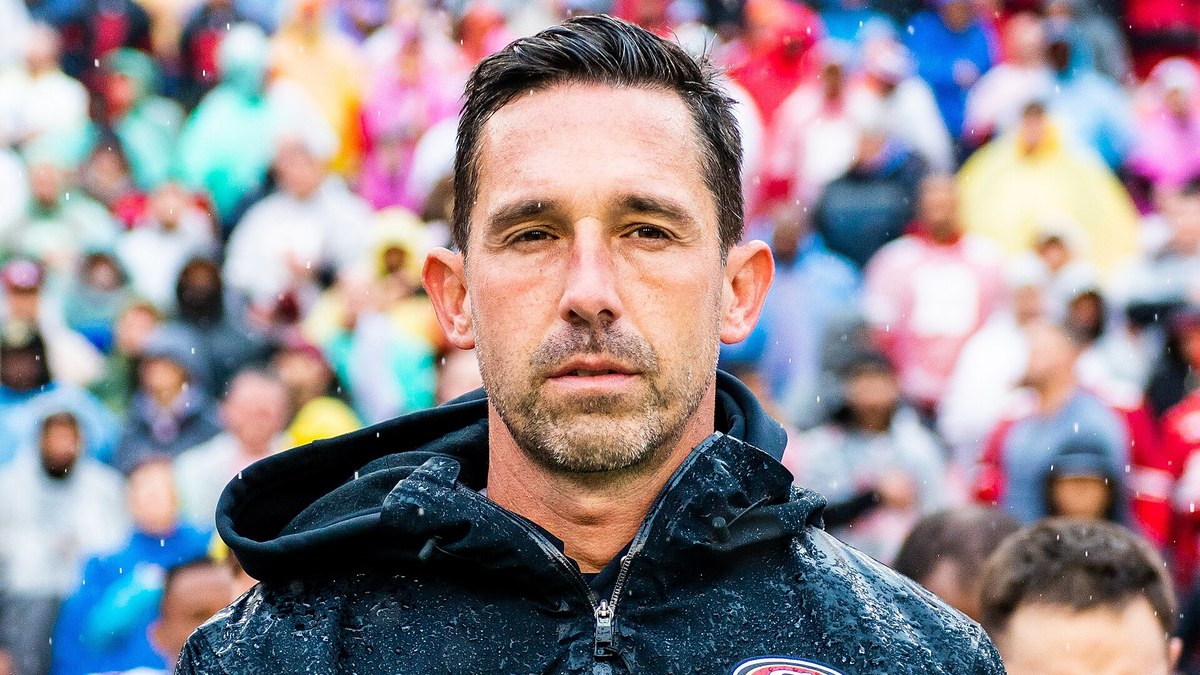 Kyle Shanahan in a rain soaked 49ers jacket on the sideline before a game