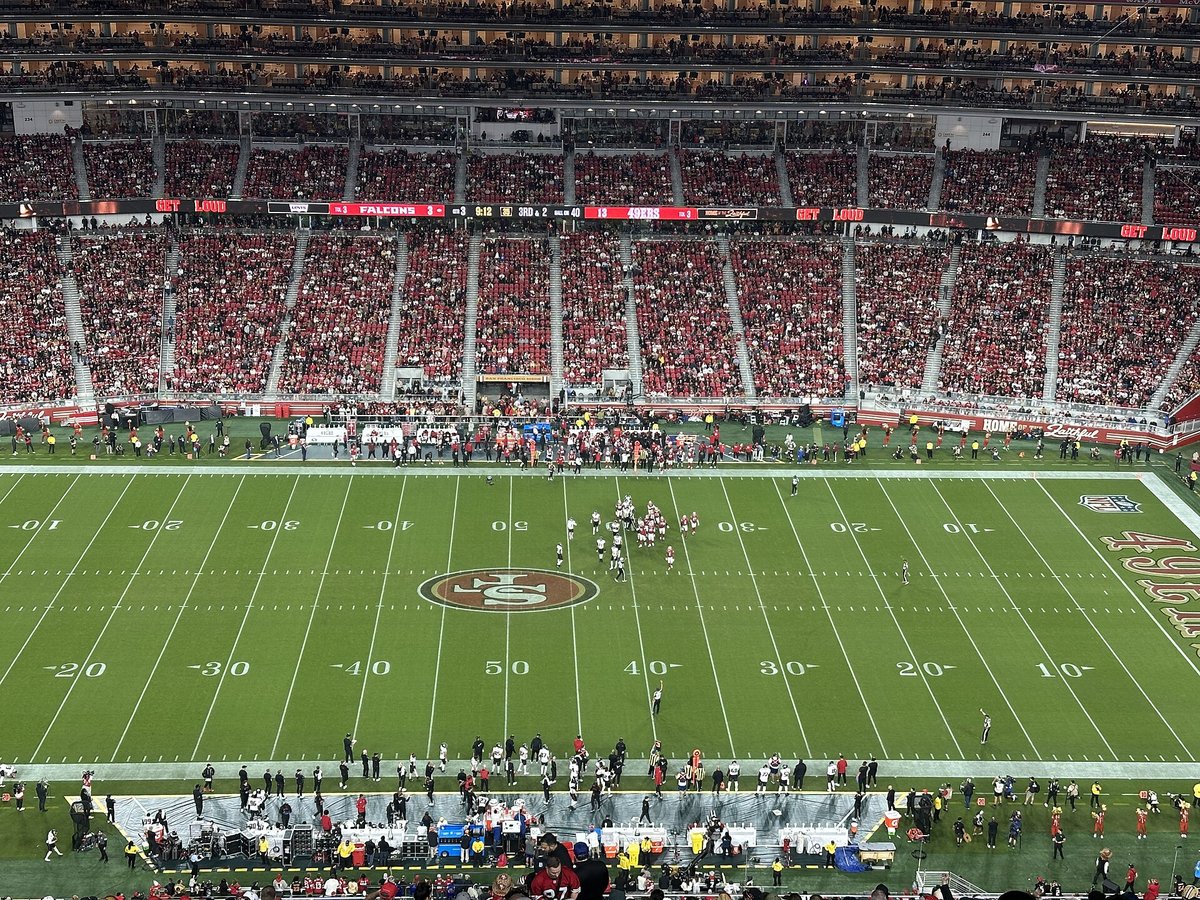 Wide view from the upper deck of the 49ers and Falcons lined up near midfield at a packed Levi's Stadium at night