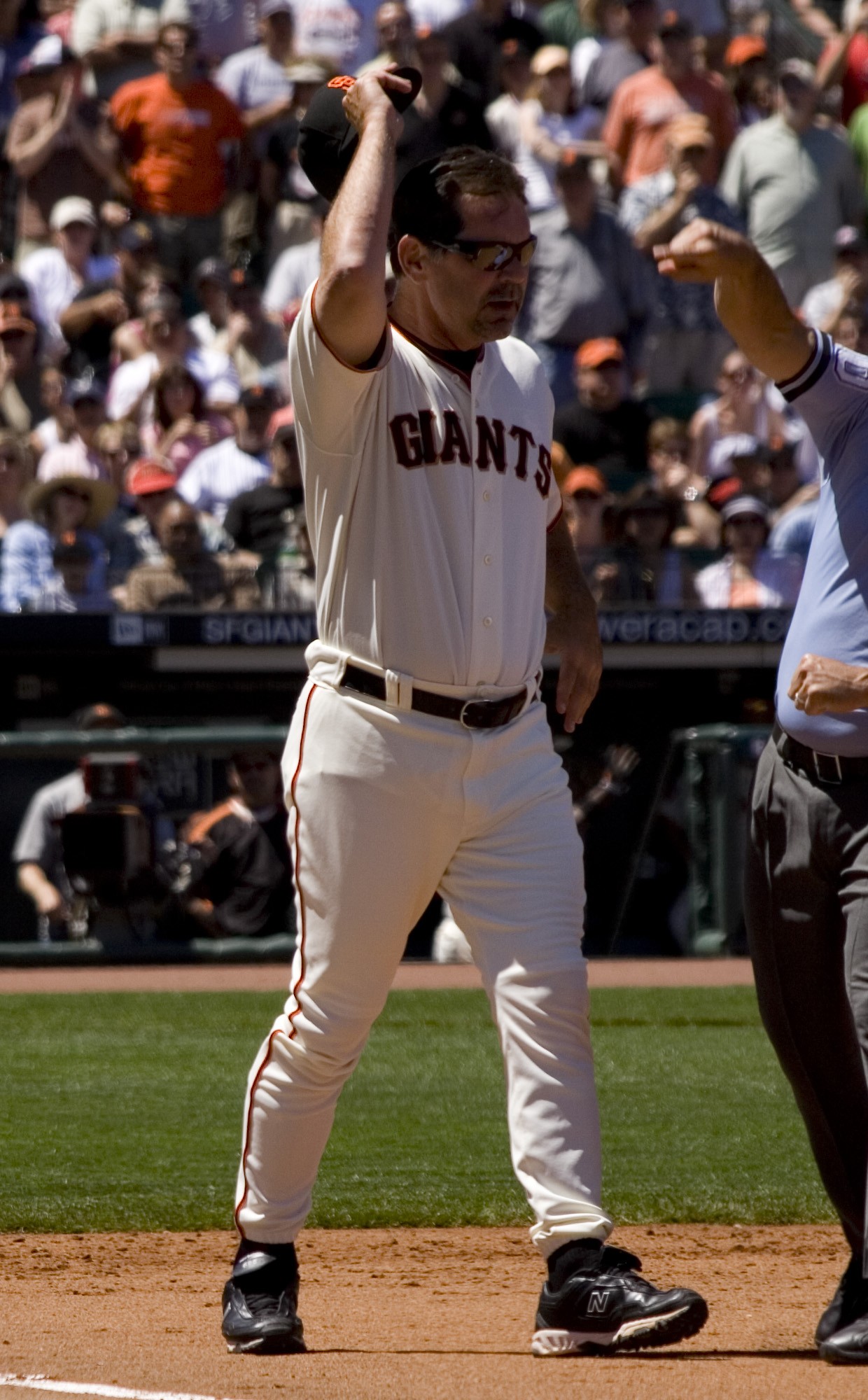 Bruce Bochy in the Giants home white uniform with sunglasses, raising his cap on the field