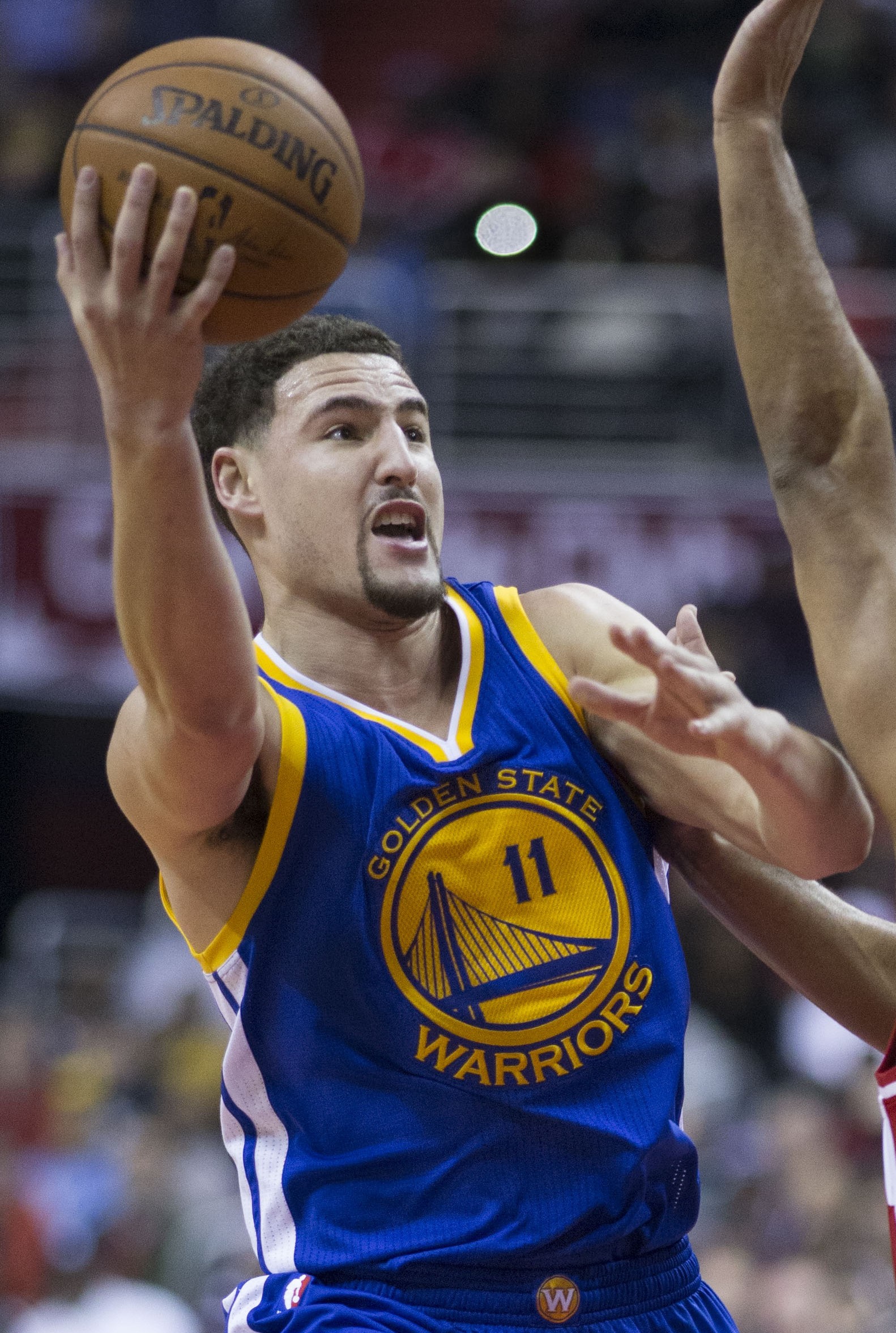 Klay Thompson in a blue Golden State Warriors number 11 jersey going up for a shot in traffic
